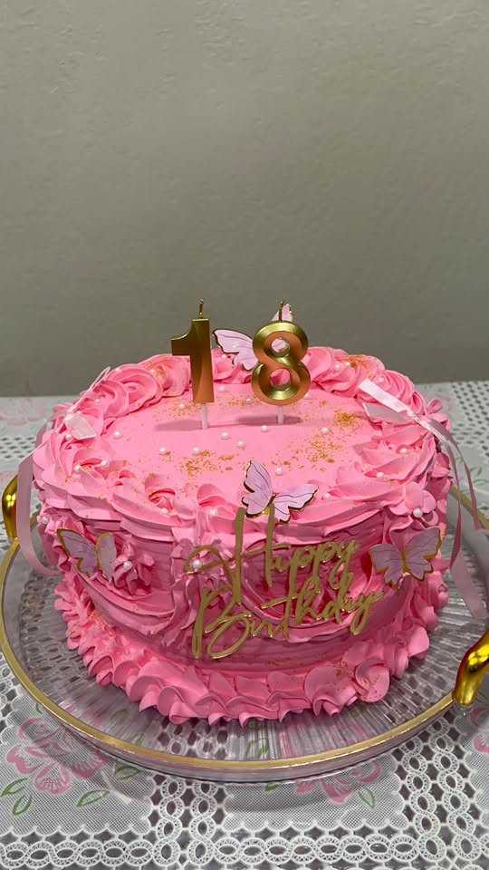 Pink ruffled 18th birthday cake with gold candles and butterflies