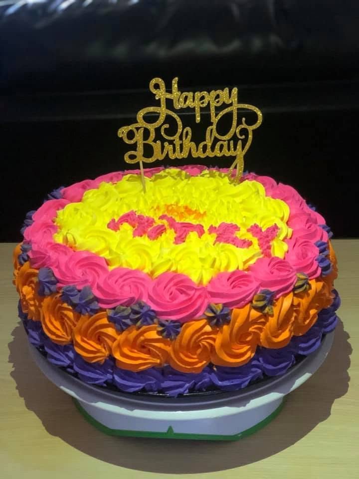 Cake piped in yellow, pink, orange and purple rosettes