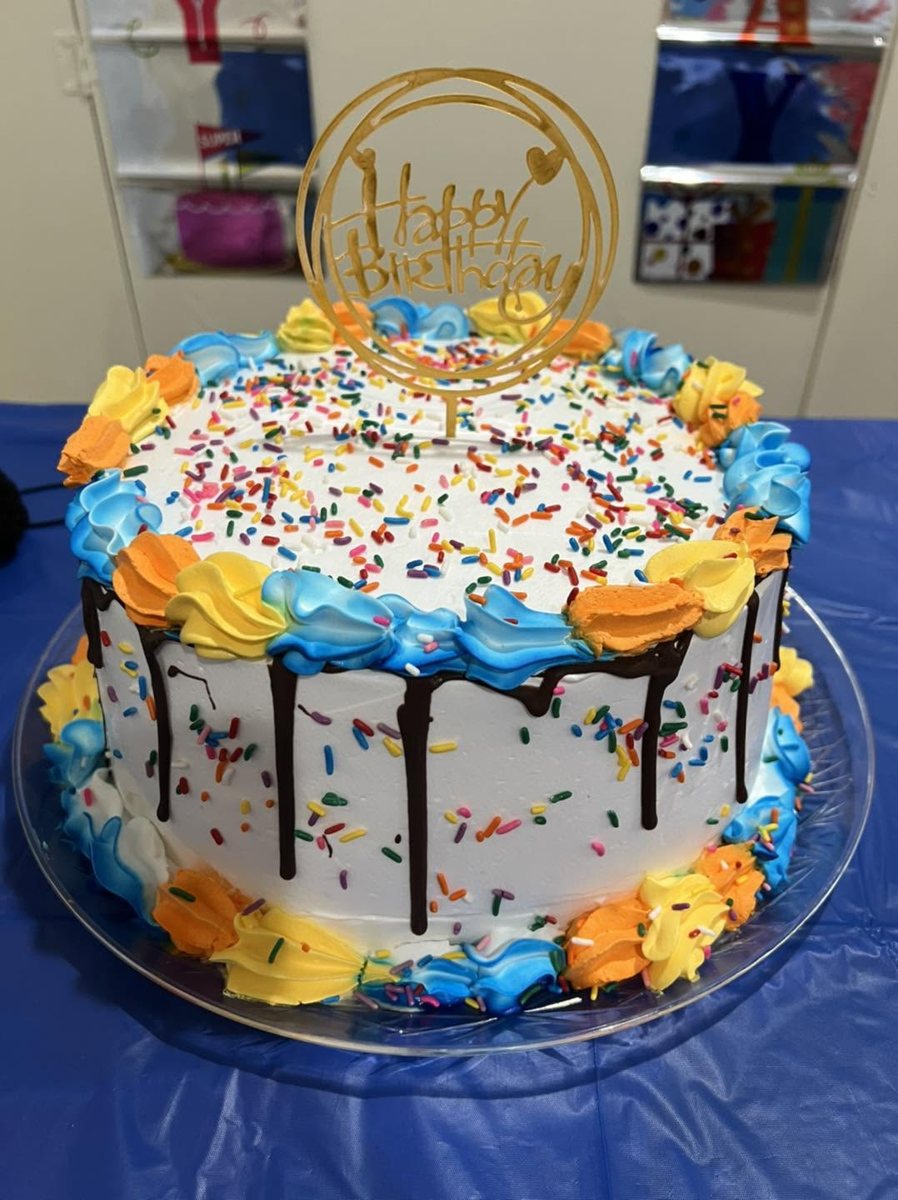 Tall sprinkle cake with chocolate drip and a Happy Birthday topper