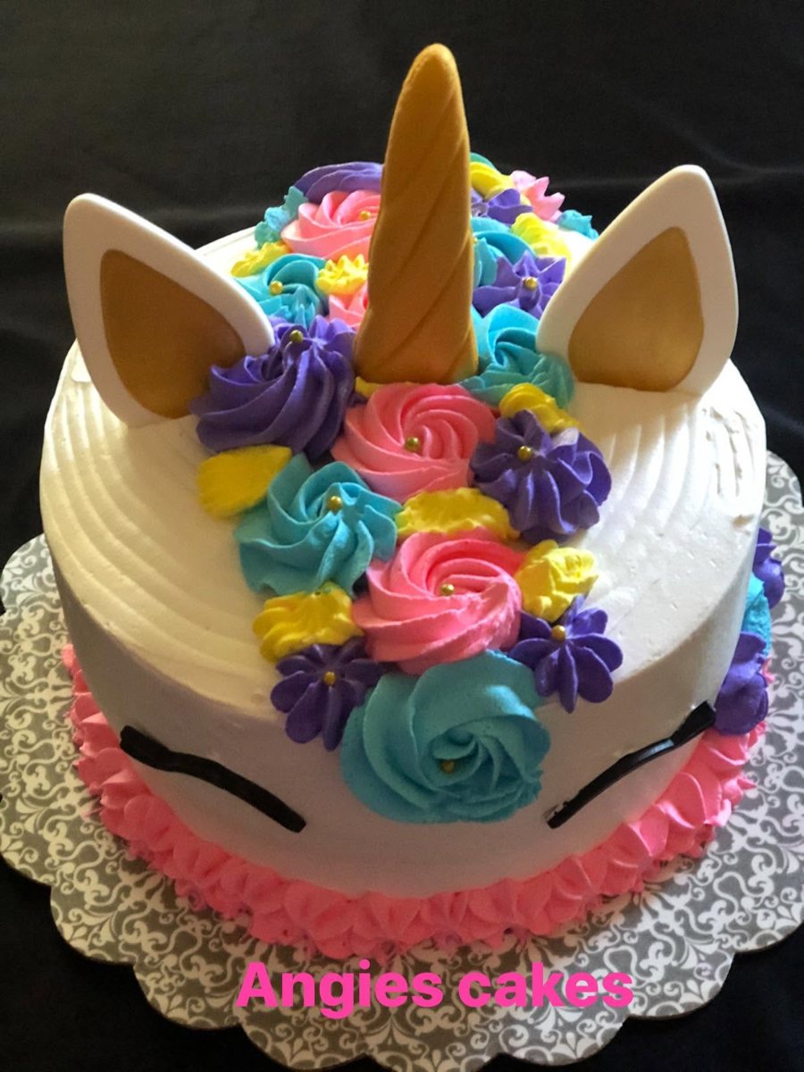 White unicorn cake with a gold horn and rainbow rosette mane